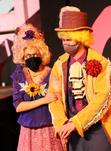 Two people in costumes stand on a stage